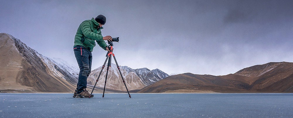 Man at Pangong lake using a tripod for photography, Ladakh