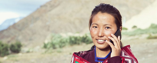 Ladakhi woman giving a call with mobile phone from a remote area in Ladakh